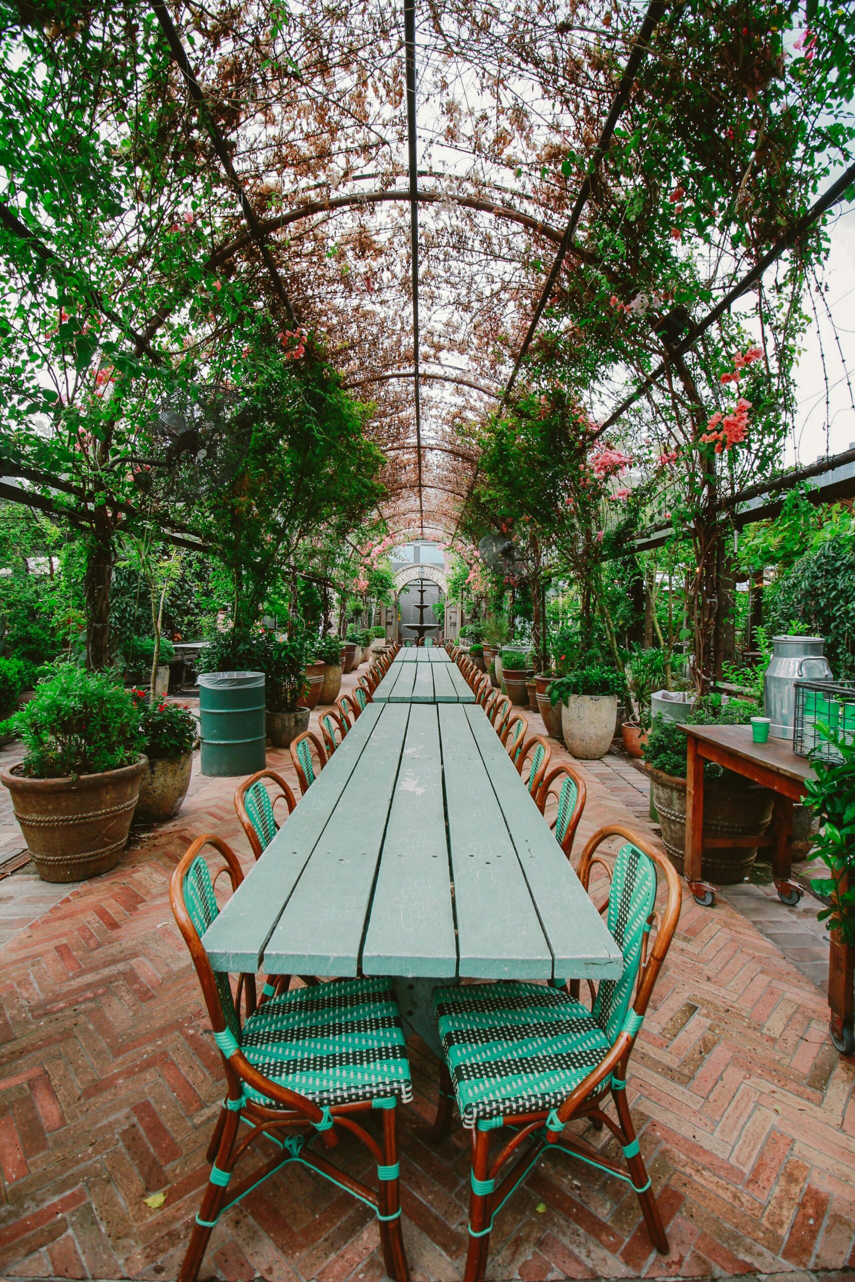 Long table under a lush floral archway, perfect for outdoor dining in a serene garden setting.